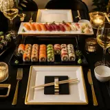 Elegancko nakryty stół z mnóstwem pysznego sushi, świecami i winem. Idealne miejsce, by cieszyć się dobrym jedzeniem, przyjaciółmi i chwilą.
