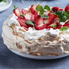 Beza z mascarpone i truskawkami, ozdobiona miętą.