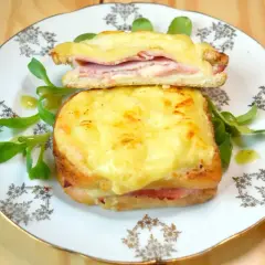 Dwie francuskie kanapki croque monsieur z serem i szynką, podane na talerzu z sałatką.