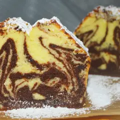 Kawałek wilgotnej babki marmurkowej z czekoladą i wanilią, posypanej cukrem pudrem.