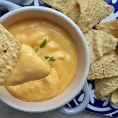 Chrupiące nachos zanurzane w kremowym sosie z serka topionego, ozdobionym gałązką ziół. Idealna przekąska na imprezę.