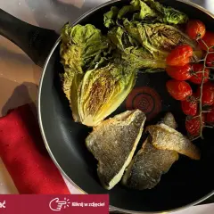 Smażona dorada z pomidorkami koktajlowymi i sałatą rzymską na patelni.