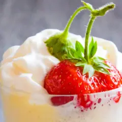 Krem zabaglione z truskawką i bitą śmietaną w szklance.