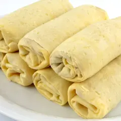 Stos naleśników zwiniętych w rulony na białym talerzu.