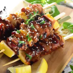 Aromatyczne yakitori z kurczaka w sosie teriyaki, posypane sezamem i szczypiorkiem, podane z cytryną.
