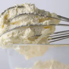 Krem z mascarpone na drucianej trzepaczce miksera, widok z bliska.