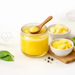 Słoik z masłem klarowanym, miseczki z masłem, liście szpinaku i przyprawy.