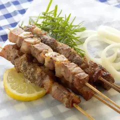 Grillowane szaszłyki z mięsa na patykach, podane z cytryną, cebulą i rozmarynem.
