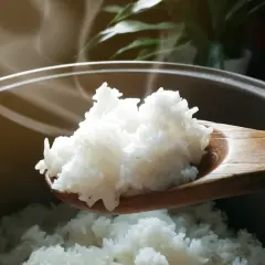 Łyżka z parującym, białym ryżem nad garnkiem.