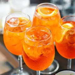 Cztery orzeźwiające drinki Aperol Spritz z lodem i plasterkami pomarańczy. Idealny aperol przepis na letnie popołudnie.