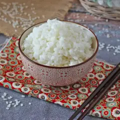 Miseczka kleistego ryżu do sushi na kolorowej serwetce z pałeczkami.