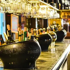 Butelki w wiaderku na lód, w tle kieliszki i inne alkohole. Zastanawiasz się, jaki alkohol ma najmniej kalorii?