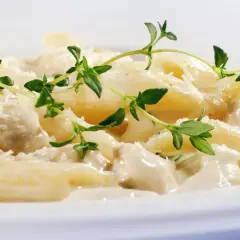 Penne w kremowym sosie z kurczakiem i parmezanem, ozdobione świeżym tymiankiem. Różne rodzaje makaronu mogą być równie pyszne!