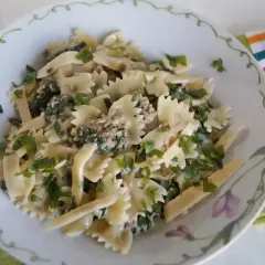 Pyszny makaron farfalle z tuńczykiem i szpinakiem, posypany świeżą natką pietruszki. Idealny na szybki obiad.