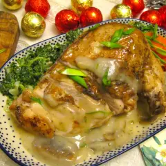 Pieczona pierś z kurczaka w sosie, podana ze szpinakiem i marchewką, ozdobiona szczypiorkiem.