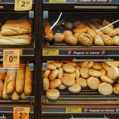 Różne rodzaje pieczywa, w tym bochenki i bułki, wystawione na sprzedaż w sklepie.