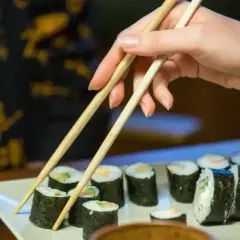 Dłoń z pałeczkami sięga po rolkę sushi. Smaczne i zdrowe, ale warto pamiętać o sushi kcal.