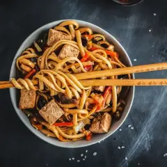 Miska domowego udonu z tofu i warzywami, podana z pałeczkami.