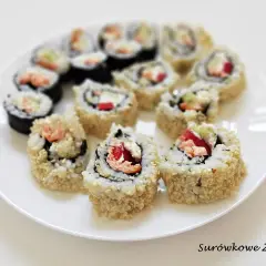 Talerz z rolkami sushi uramaki z ryżem na zewnątrz, posypanymi sezamem, z łososiem i warzywami.