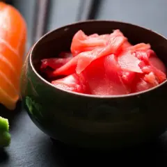 Miseczka z różowym, marynowanym imbirem obok sushi i wasabi. Idealny dodatek do japońskich przysmaków.