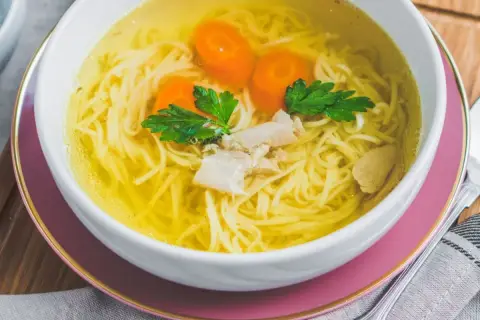Aksamitny rosół z makaronem, kawałkami kurczaka i marchewką, jak z przepisu Magdy Gessler. Idealny na chłodne dni.