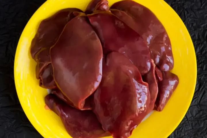 Surowa wątróbka drobiowa na żółtym talerzu. Zastanawiasz się nad wątróbka drobiowa kcal?