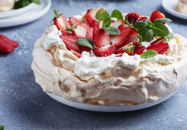 Beza z mascarpone i truskawkami, ozdobiona miętą.
