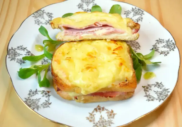 Dwie francuskie kanapki croque monsieur z serem i szynką, podane na talerzu z sałatką.