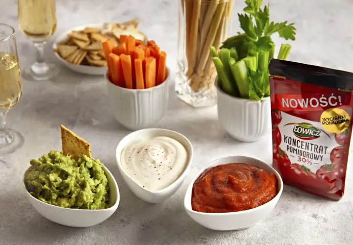 Trzy miseczki z dipami: guacamole, śmietanowym i pomidorowym, obok warzyw i krakersów.