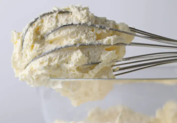 Krem z mascarpone na drucianej trzepaczce miksera, widok z bliska.