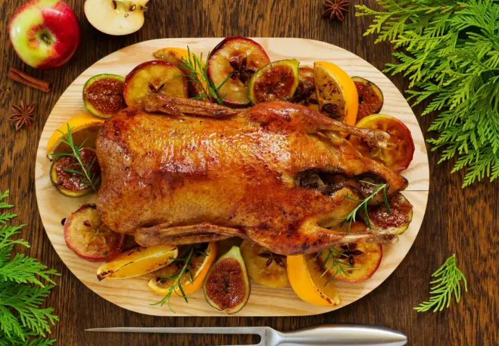 Pieczona kaczka w pomarańczach, jabłkach i figach, ozdobiona rozmarynem. Aromatyczne danie świąteczne.