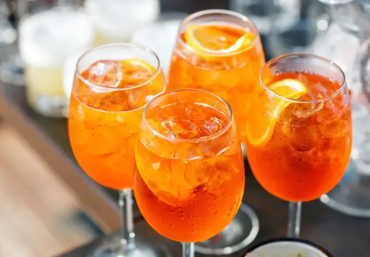 Cztery orzeźwiające drinki Aperol Spritz z lodem i plasterkami pomarańczy. Idealny aperol przepis na letnie popołudnie.