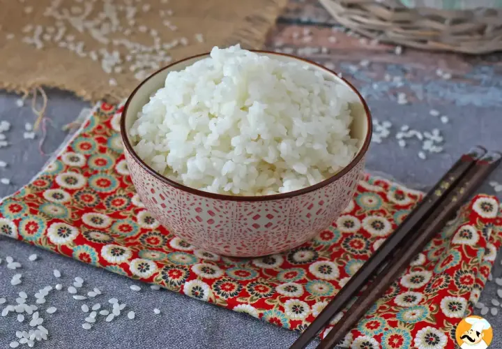 Miseczka kleistego ryżu do sushi na kolorowej serwetce z pałeczkami.