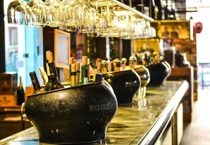 Butelki w wiaderku na lód, w tle kieliszki i inne alkohole. Zastanawiasz się, jaki alkohol ma najmniej kalorii?