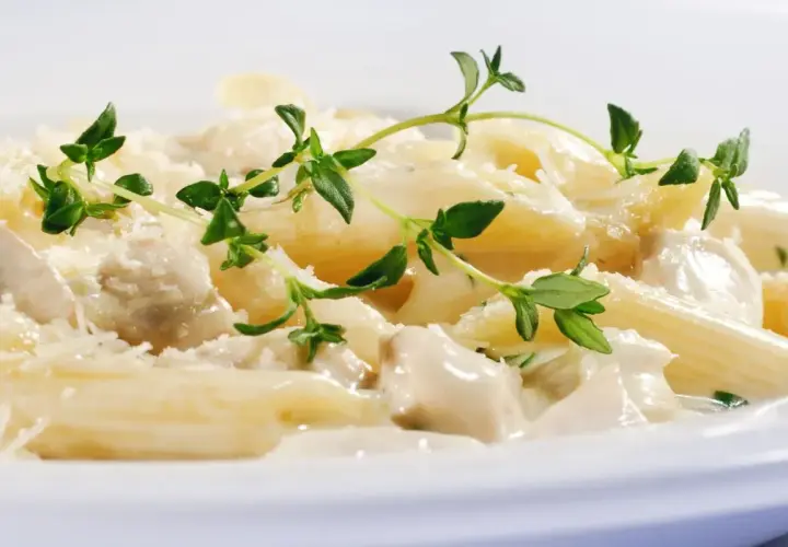 Penne w kremowym sosie z kurczakiem i parmezanem, ozdobione świeżym tymiankiem. Różne rodzaje makaronu mogą być równie pyszne!