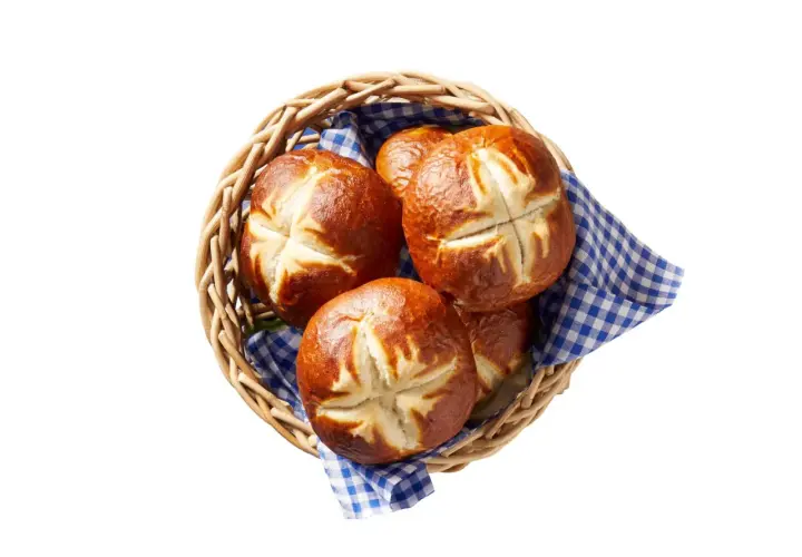Koszyk z chrupiącymi bułkami bawarskimi, ozdobiony niebiesko-białą kratką. Idealne na śniadanie.