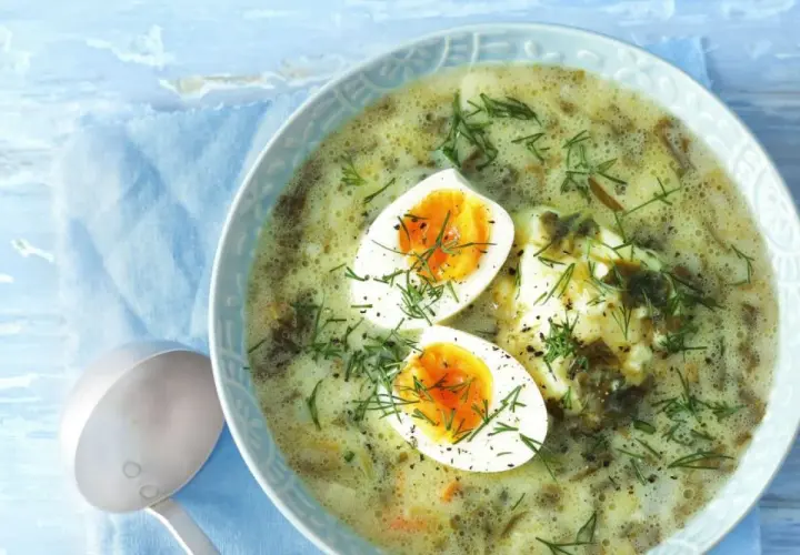 Zupa szczawiowa z jajkiem i koperkiem w misce, obok chochla.