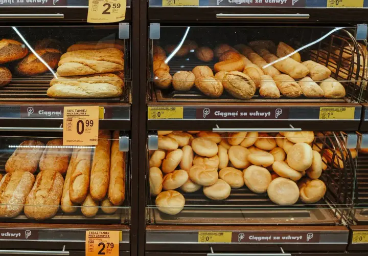 Różne rodzaje pieczywa, w tym bochenki i bułki, wystawione na sprzedaż w sklepie.