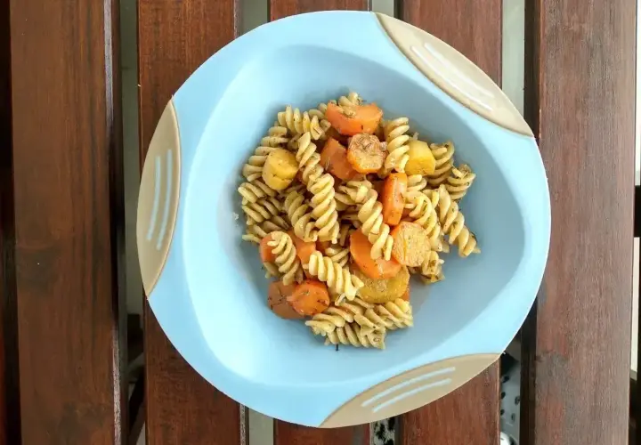 Makaron fusilli z marchewką i ziemniakami na niebieskim talerzyku.