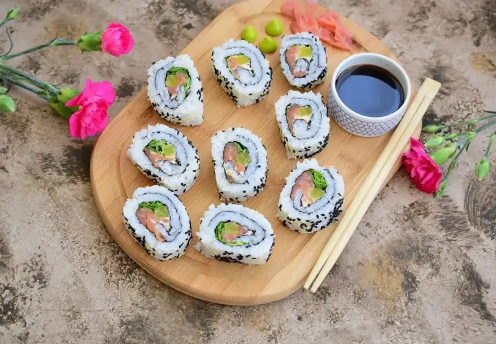 California sushi z łososiem i awokado, posypane czarnym sezamem, podane z sosem sojowym i wasabi.