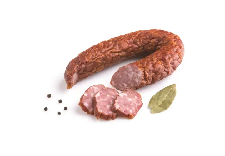 Kiełbasa jałowcowa w całości i w plasterkach, z ziarnami pieprzu i liściem laurowym.