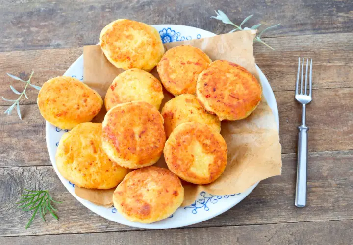 Talerz pełen złotych placków kukurydzianych (arepas) z widelcem obok.