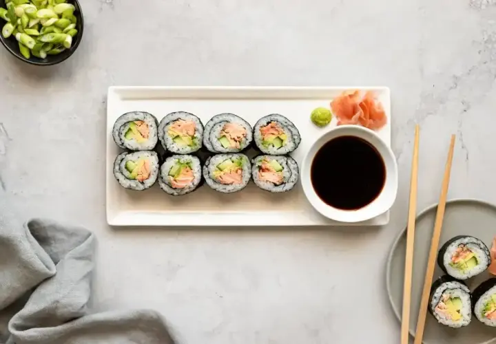 Talerz z hosomaki, miseczka sosu sojowego, wasabi, marynowany imbir i szczypiorek.
