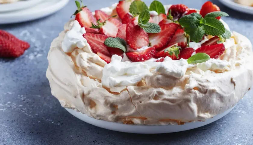 Beza z mascarpone i truskawkami, ozdobiona miętą.