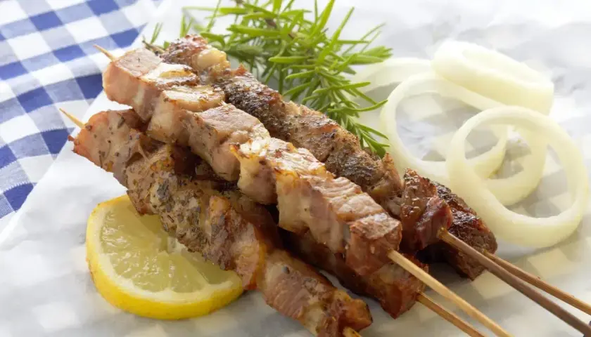 Grillowane szaszłyki z mięsa na patykach, podane z cytryną, cebulą i rozmarynem.