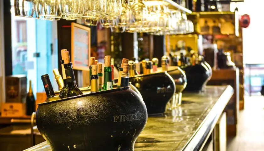 Butelki w wiaderku na lód, w tle kieliszki i inne alkohole. Zastanawiasz się, jaki alkohol ma najmniej kalorii?