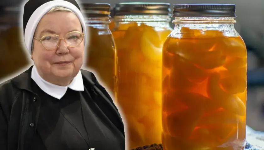 Zakonnica obok słoików z gruszkami w zalewie.