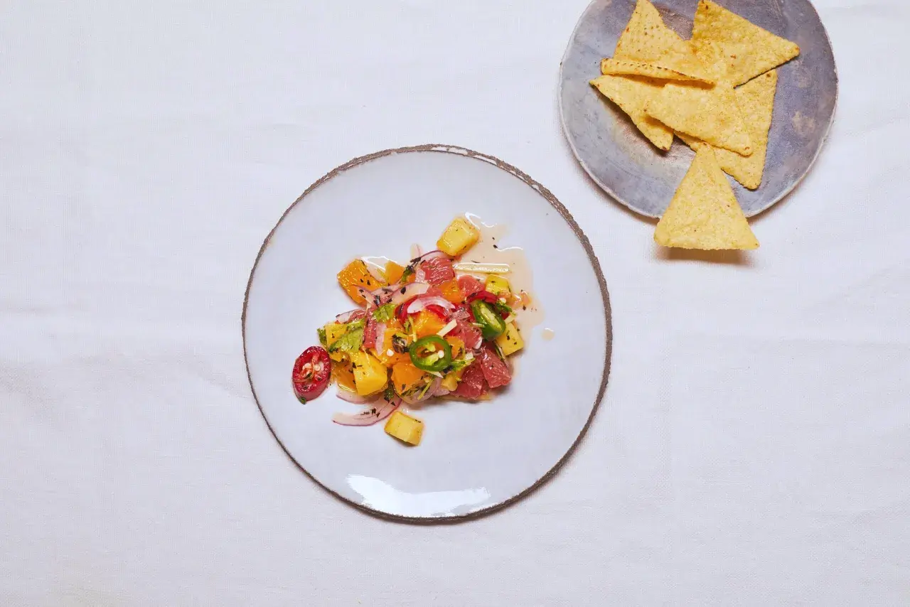 Kolorowe ceviche z owocami cytrusowymi, papryczką chili i cebulą, obok nachos.