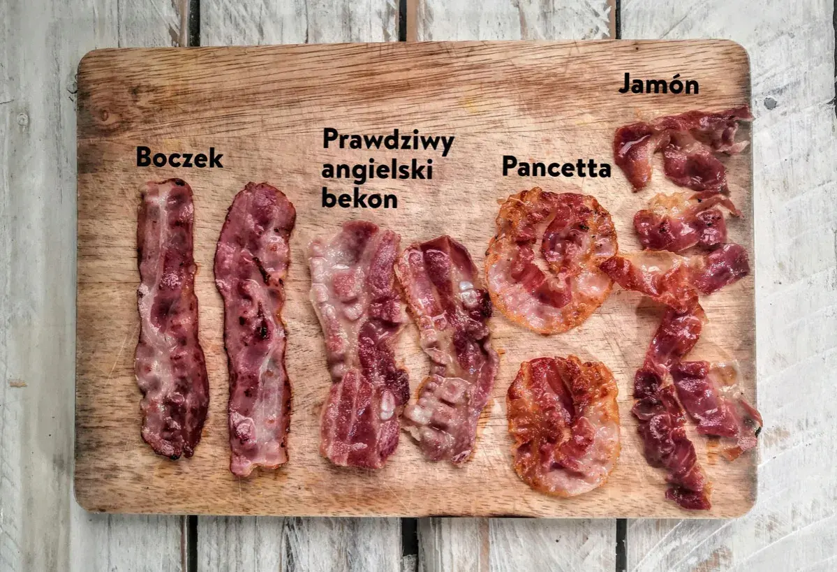 Różne rodzaje boczku: polski, angielski, pancetta i jamón, ułożone na desce.