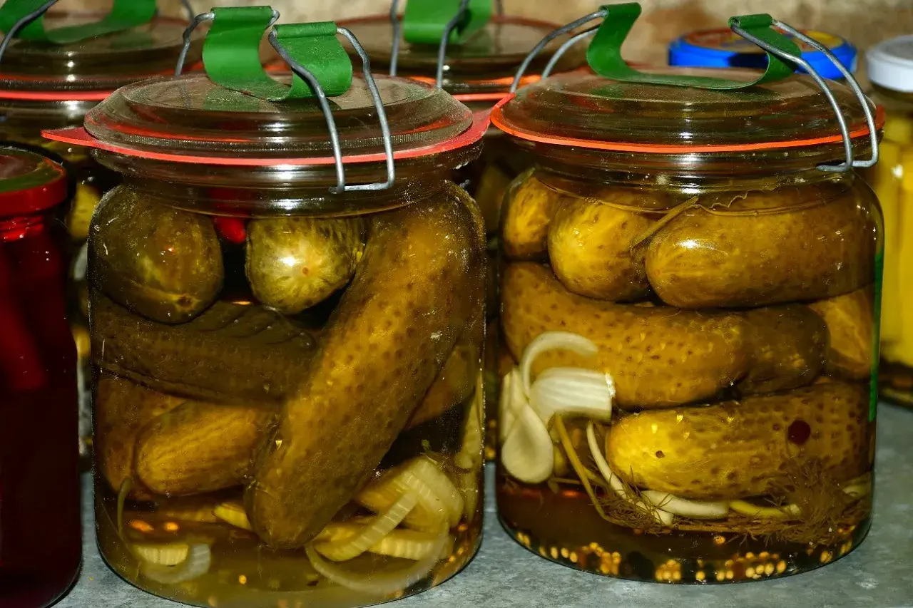 Słoiki z ogórkami kiszonymi, z dodatkiem cebuli i przypraw.